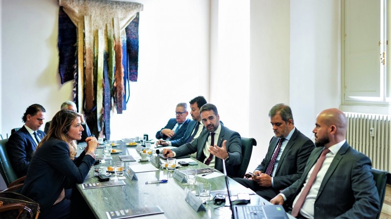 Leite sentado a uma mesa de reunião falando e gesticulando enquanto apresenta o RS a investidores italianos. Na mesa com ele seis homens e uma mulher.