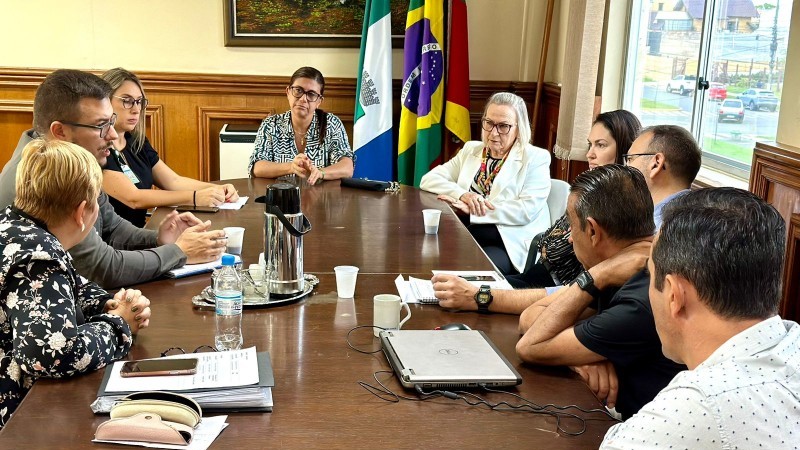 Imagem de uma reunião da comissão de transição do Hospital Tramandaí. Sentados À mesa estão quatro homens e três mulheres.