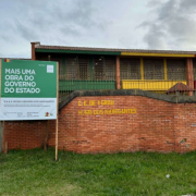 Imagem da fachada da Escola Nossa Senhora dos Navegantes, em Pelotas com um placa indicativa de Mais Uma Obra do Governo do Estado.