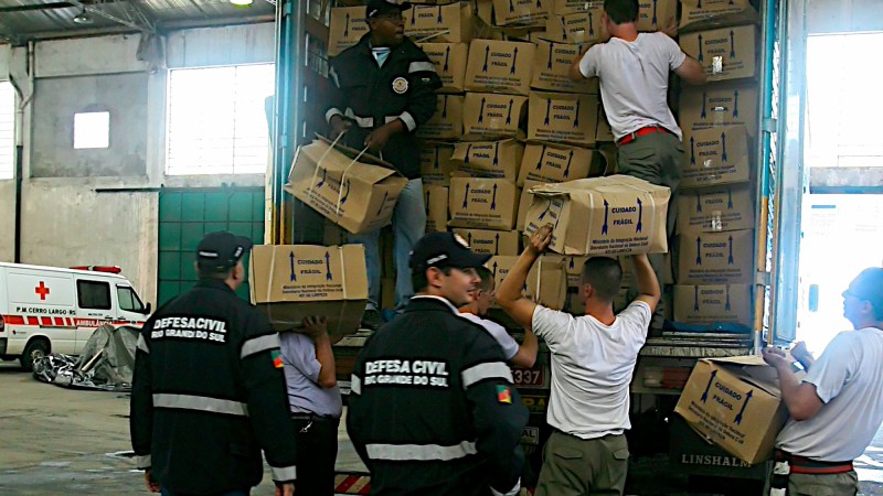 Integrantes da Defesa Civil do Estado preparam caminhões carregados com colchões, cestas básicas e kits de limpeza para serem encaminhados às regiões de Santa Rosa e Cerro Largo.