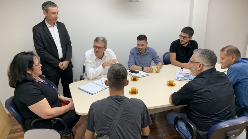 Em torno de uma mesa de reunião, várias pessoas, entre as quais o secretário de Trabalho e Desenvolvimento Profissional, Gilmar Sossela. Também estão presentes servidores da pasta e da FGTAS, além de um dos trabalhadores resgatados na Serra em situação análoga à escravidão.