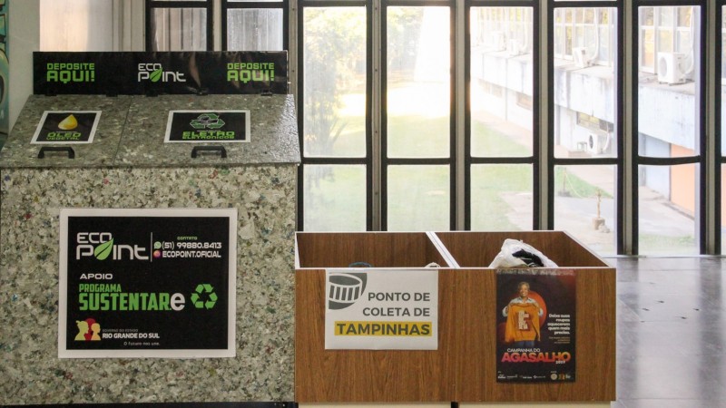 Dois pontos de coleta do programa Sustentare, disponibilizados no hall de um prédio. Um é para óleo usado e eletrônicos; o outro, para coleta de tampinhas