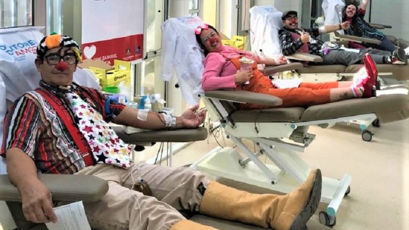 Pessoas caracterizadas com roupas de palhaço doando sangue