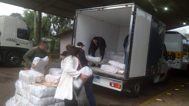 Pessoas retiram cestas básicas da carga de um caminhão a fim de organizar a distribuição dos alimentos