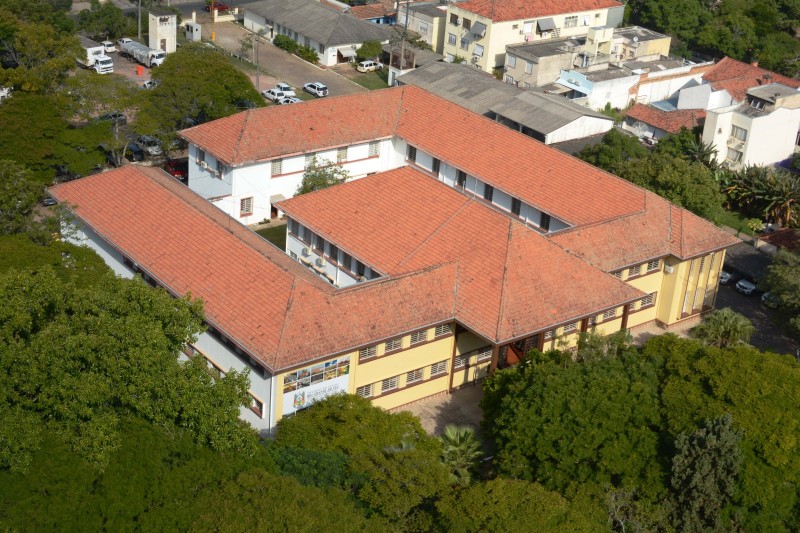 De cima, o edifício da Seapi, de poucos andares, formato de quadrado e pátio interno. Ao redor, há muitas árvores