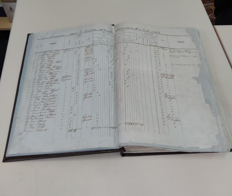 Documento, que parece um grande livro, aberto. Suas páginas são brancas e há várias marcações à caneta