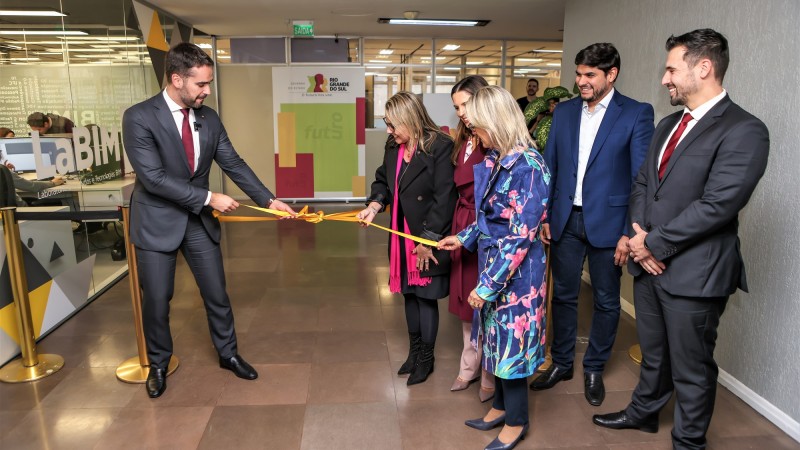 À esquerda da imagem, o govenador Eduardo Leite está ao lado do LaBIM, desfazendo o laço da fita que também é segurada por outras duas mulheres, uma delas a titular da SPGG. Além delas, mais três pessoas que participam do ato se encontram na imagem, mais à direita.