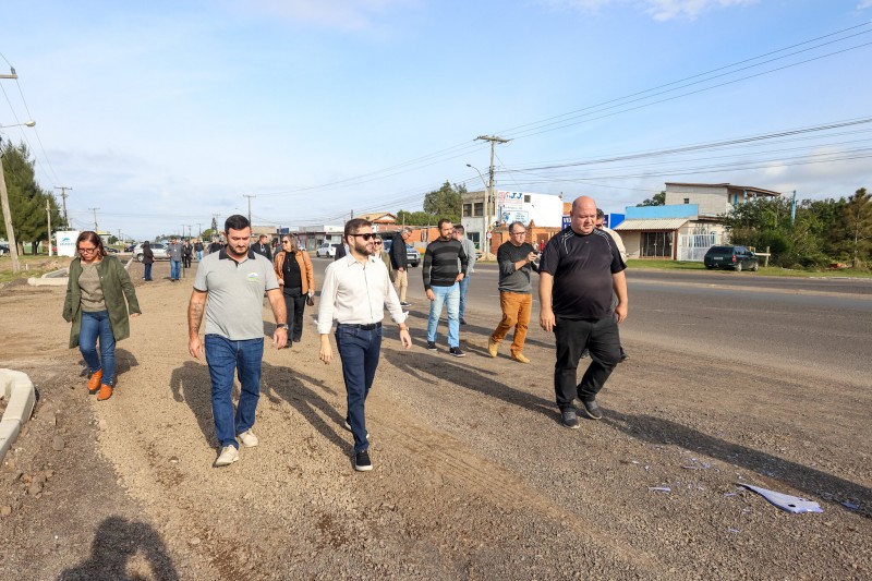 Numa avenida em obras, Gabriel Souza anda no meio rodeado por pessoas que o seguem. O céu está claro.