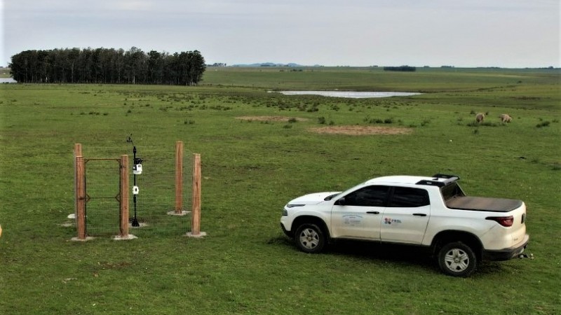 Imagem de um campo aberto no qual pode ser visto um carro da Seapi à direita e uma das novas estações meteorológicas instaladas na semana passada.