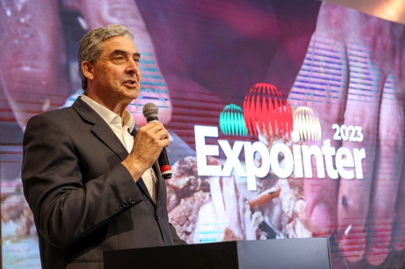 Em ambiente fechado, com a marca da Expointer 2023 ao fundo, secretário Giovani Feltes fala ao microfone no lançamento do evento.