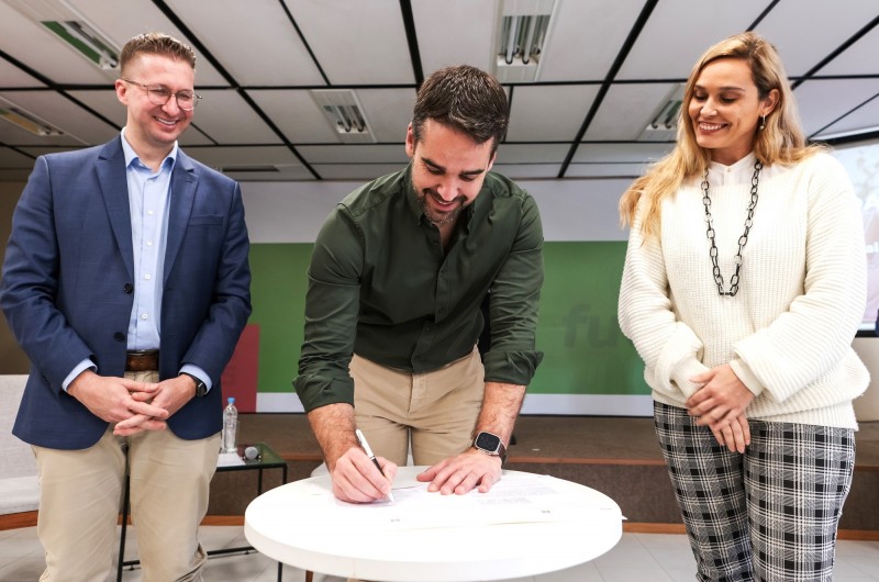 Leite ao centro assinando o documento da parceria para o programa Empreendedor Social RS. À esquerda, Beto Fantinel, e, à direita, Helena Casanovas.
