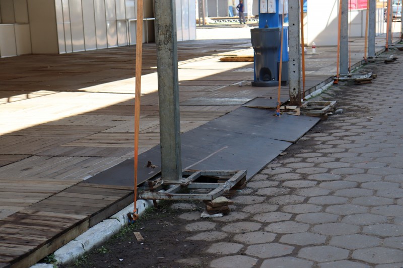 Uma rampa preta, de baixa inclinação, aparece instalada junto a uma calçada.