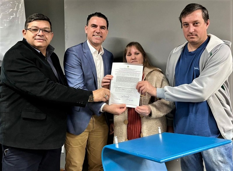 Foto de um casal que mora no loteamento Santa Luiza recebendo o documento das mãos do secretário de Habitação e Regularização Fundiária e do prefeito de Sapucaia do Sul.