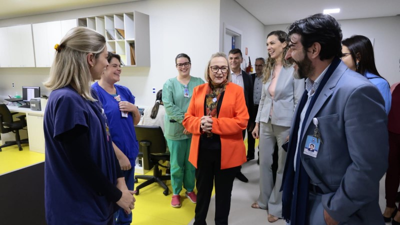Numa sala de hospital, Arita está de pé, ao meio. Ela se encontra rodeada por outras pessoas de pé, que com ela interagem e riem. Algumas trajam roupas típicas de hospital. As paredes são brancas, no fundo há mesas e cadeiras de escritório.