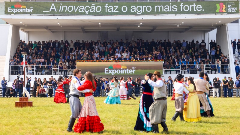 Casais de peões e prendas do CTG Independência Gaúcha, de Esteio, dançam no gramado da pista central do Parque de Exposições Assis Brasil, durante a cerimônia oficial da 46ª Expointer, diante da tribuna de honra.