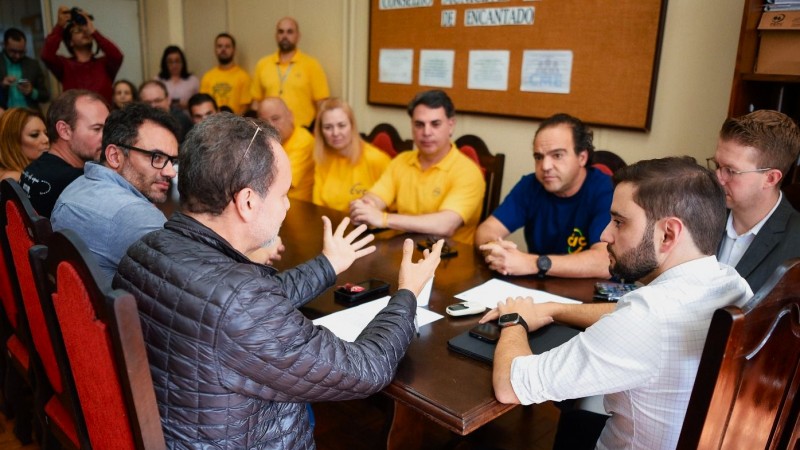 Reunião sobre o Trem dos Vales. O vice-governador está sentado à cabeceira da mesa e há pessoas sentadas dos dois lados. Na imagem, ele ouve atento uma delas.