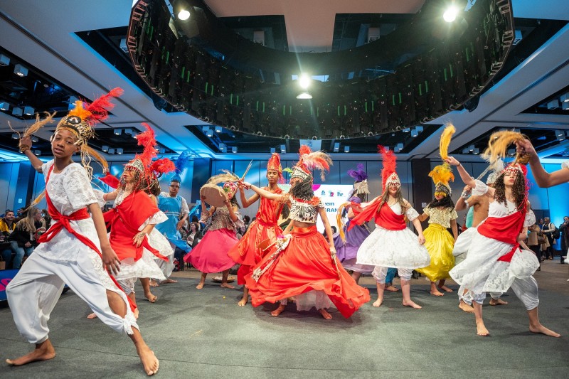 Vários jovens com trajes de origem africana realizando uma apresentação de dança no lançamento do Jovem de Futuro.