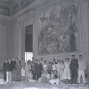 Foto em preto-e-branco mostra um grupo de, mais ou menos, 30 jovens posando para a câmera em frente à pintura do Locatelli. As vestimentas (com vestidos rendados e ternos de corte antigo) indicam que a fotografia parece ser dos anos 1960.