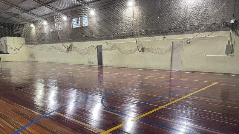 Foto do ginásio da escola Edson Figueiredo, com destaque para o piso da quadra. 