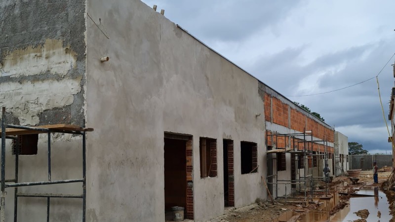 Imagem externa mostra a fachada em construção do 33º Batalhão de Polícia Militar Irmãos Murussi. Há andaimes próximos à estrutura. Parte da parede está rebocada com cimento e parte está com tijolos à vista. As aberturas, como portas e janelas, ainda não foram colocadas.