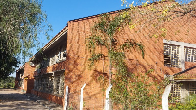 Foto em que aprecem a fachada e uma das laterais da escola. Com destaque para os tijolos à mostra que foram pintados na reforma.