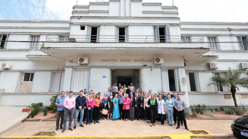 Imagem da fachada do hospital, que tem dois andares, com diversas pessoas que participaram da reinaugura&ccedil;&atilde;o reunidas na frente para a foto.