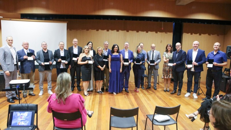 Foto posada em que diversos representantes da empresas homenageadas estão de pé, lado a lado, segurando a placa de homenagem.
