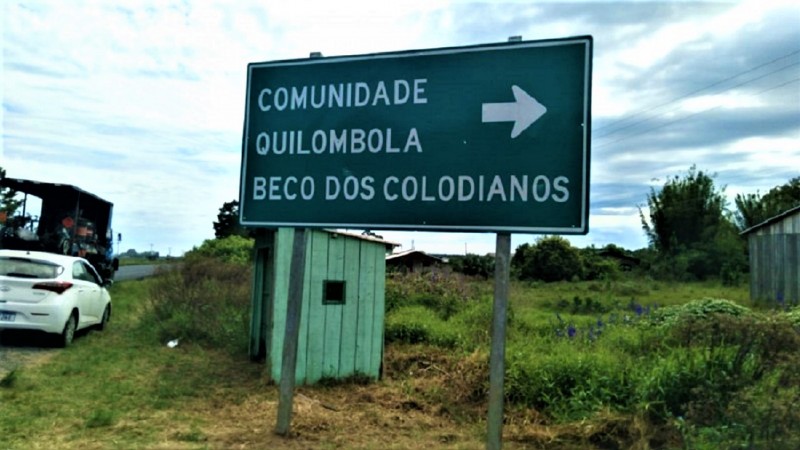 Placa de trânsito indicando a direção de acesso à comunidade quilombola Beco dos Colodianos. 