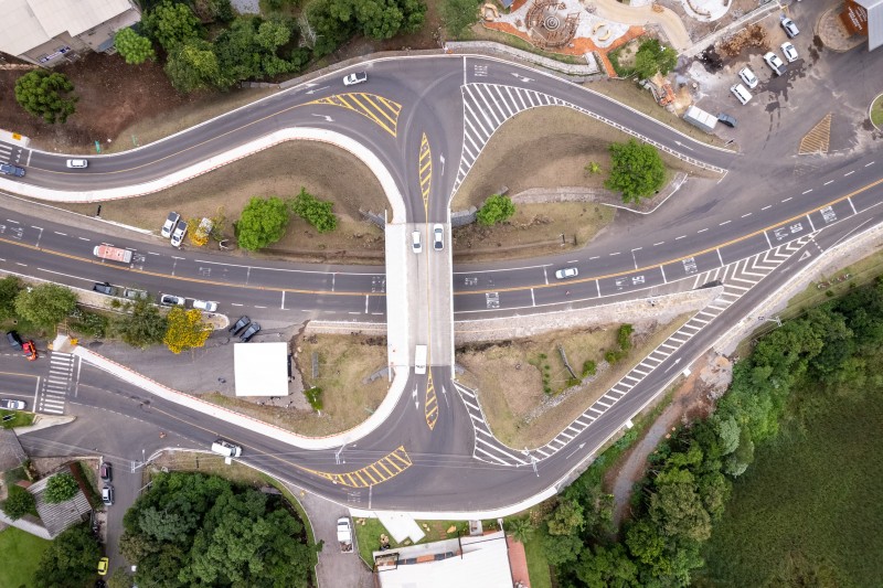 Foto aérea do viaduto, que corta estrada logo abaixo. O asfalto apresenta boas condições. Ao redor, há vegetação.