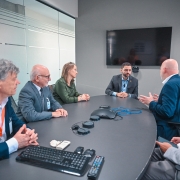 Imagem de uma mesa de reunião. O vice-governador está sentado à cabeceira da mesa. Há dois homens do lado direito e uma mulher e dois homens do lado esquerdo da mesa.