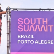 Um homem no alto em um guindaste acertando os últimos detalhes em um painel South Summit Brazil Porto Alegre na véspera do SSB 2024.