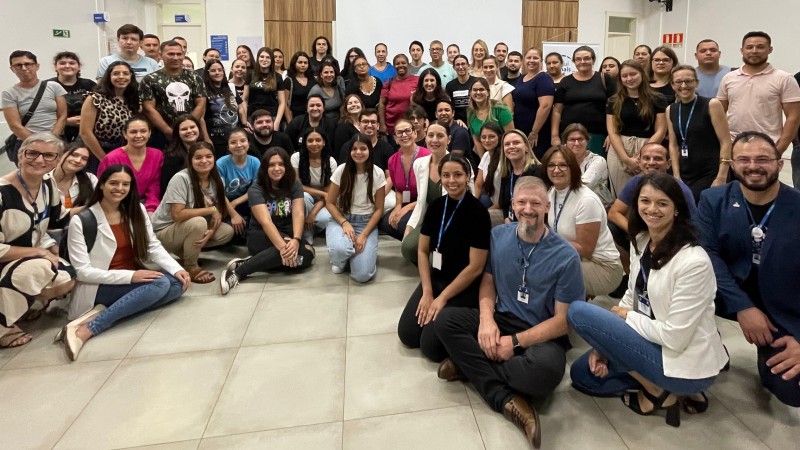 Foto em ambiente interno. Posando para a câmera, aparecem diversos estudantes e professores da Unijuí, participantes do programa. Ao centro, em meio aos jovens, está a titular da Sict.