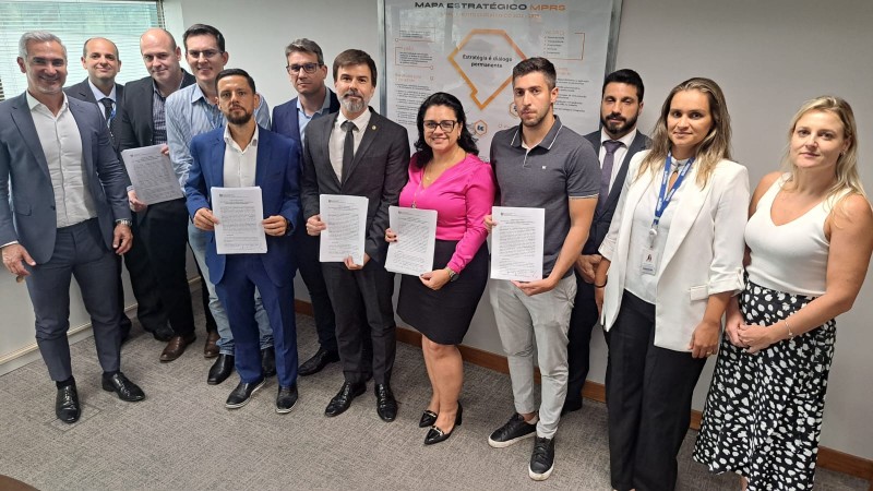 Foto posada na qual podem ser vistos nove homens e três mulheres. Alguns deles seguram o documento que foi assinado na reunião.
