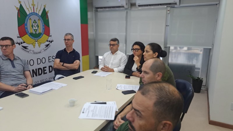 Sala de reuni&atilde;o com pessoas sentadas ao redor de uma mesa