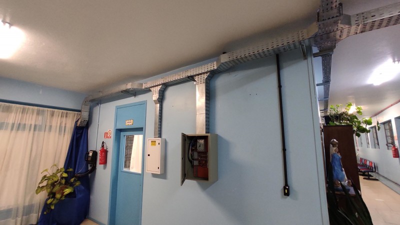 Foto de uma parede azul onde estão instalações elétricas novas e bem protegidas por grades.