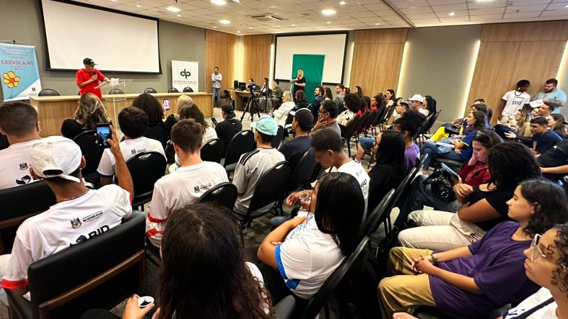 Foto lateral do Seminário sobre cultura de paz e direitos de crianças e adolescentes. Mais esquerda e no alto um homem fala para a plateia. No restante da imagem, pode ser vista a plateia, parte dela de costas e parte dela de perfil.