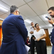 Leite falando ao celular em pé e observado por quatro pessoas. 