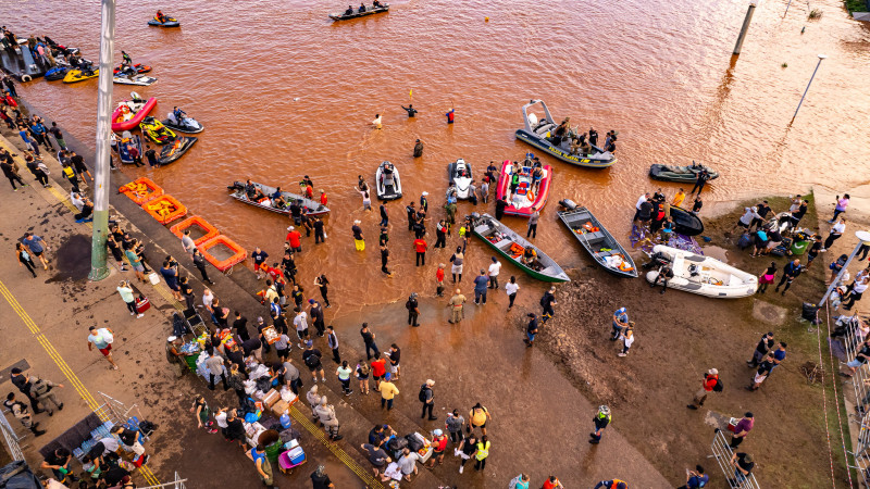 Barcos estacionados e pessoas em local alagado 2024