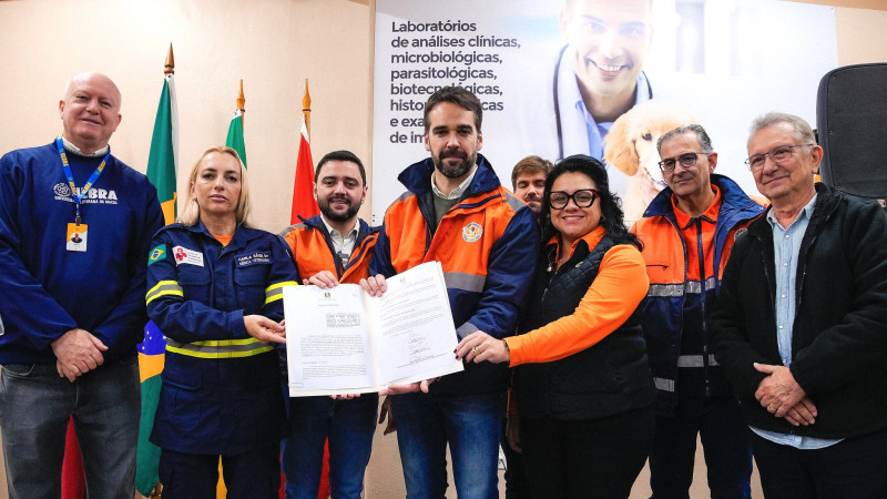 Diversas pessoas segurando o documento do acordo para assistência de animais resgatados após as enchentes.