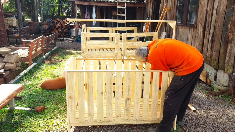 Um homem de perfil e curvado atua na construção de um berço