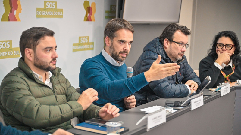 Reunião com pesquisadores do Instituto de Pesquisas Hidráulicas da UNFRGS. Leite falando ao microfone e três pessoas aso seu lado na mesa olham para ele.