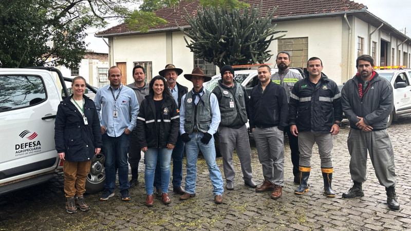 Foto posada da equipe da São Paulo que veio ajudar a Seapi. Eles estão em pé e reunidos na frente das caminhonetes nas quais chegaram ao RS.
