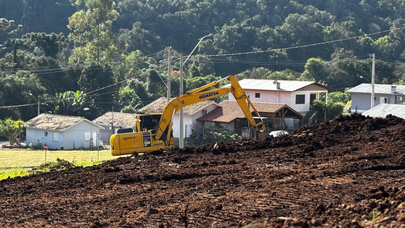 Foto de escavadeira trabalhando em ambiente aberto, no meio da terra.