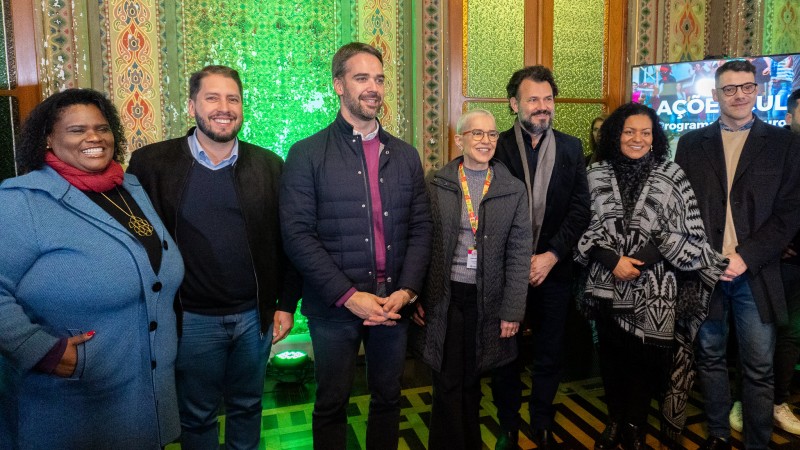 Foto posada em ambiente fechado, com Leite sorrindo ao centro, em pé. Há mais três mulheres e três homens perfilados.