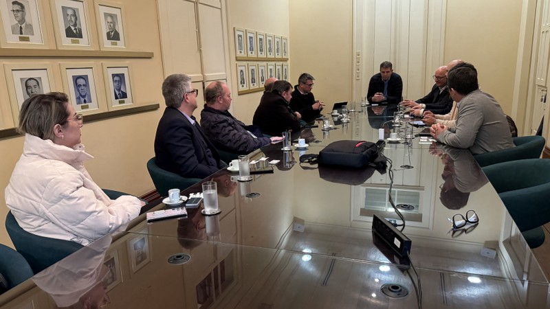 Reunião sobre implantação de empresa de fertilizantes no RS. Todos os participantes estão sentados em torno de uma mesa.