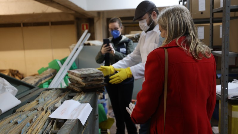 Comitiva da Unesco visita arquivos do Caff. Na imagem, três pessoas analisam pastas e papéis dentro de um dos arquivos.