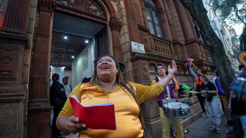 Imagem de artistas fazendo uma performance na rua diante de um Museu durante cortejo no dia do Patrimônio de 2023.