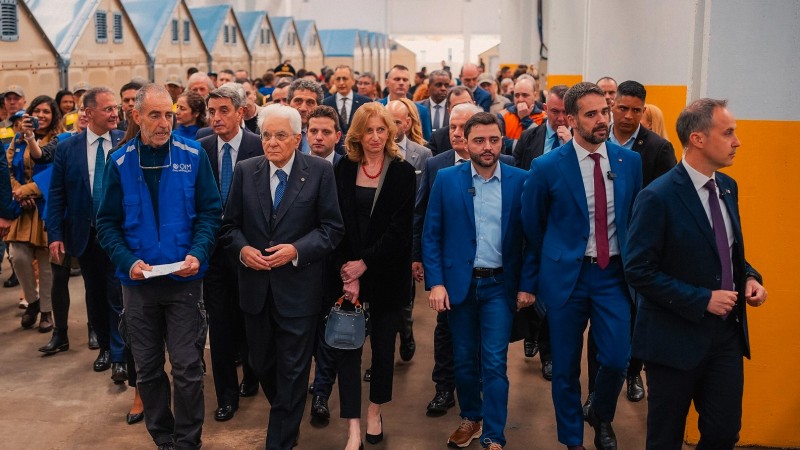 Leite, Gabriel e o presidente da Itália com muitas pessoas atrás deles enquanto percorriam o espaço do Centro Recomeço.