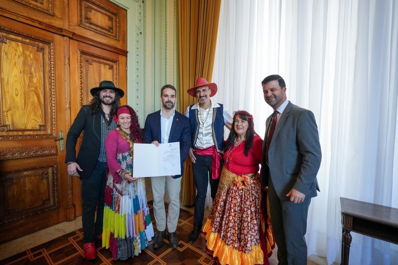 Foto posada de Leite com ciganos e o deputado autor da Lei segurando o documento recém-assinado.
