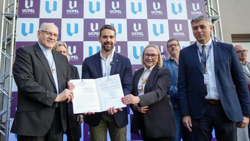 Leite e outras pessoas segurando o documento recém assinado na inauguração de ambulatórios do Hospital Universitário de Pelotas.